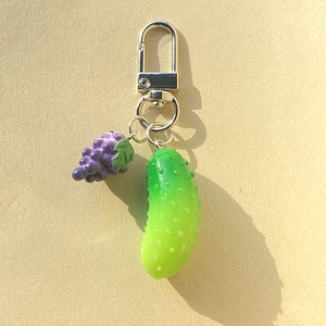 Detail of creative resin purple grape and green cucumber charms on a silver metal keychain