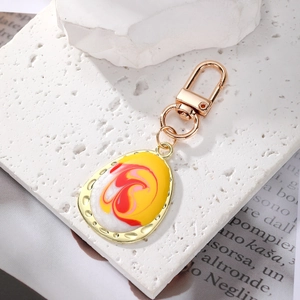 Detail of bohemian enamel keychain with yellow and red marbling in a gold frame