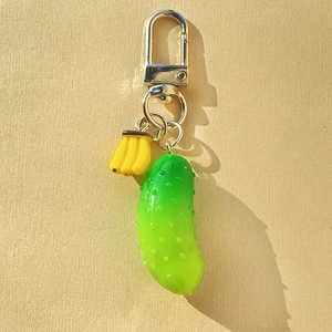 Funny realistic cucumber and small banana keychain with silver lobster clasp on beige paper