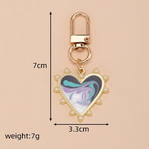 Detail view of heart-shaped marble keychain with pearl accents and size dimensions