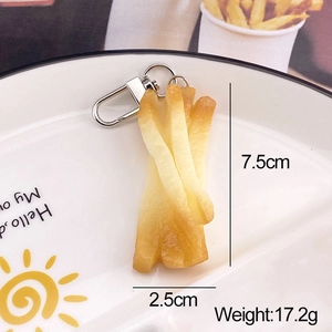 Macro detail of a 7.5cm wavy french fry keychain pendant on a white ceramic plate