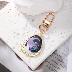 Detail of bohemian geometric keychain with purple marble enamel swirl and gold plating