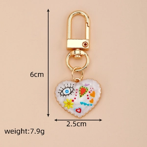 Detail view of heart-shaped keychain with colorful eye pattern and golden metal hook