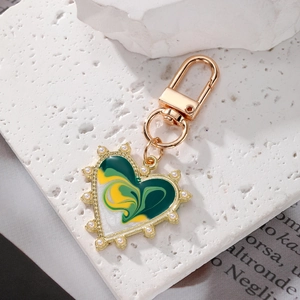 Close-up of golden heart keychain with marble enamel inlay and elegant pearl border