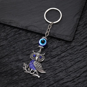Portachiavi gufo vintage con perla malocchio e strass blu su fondo in pietra scura
