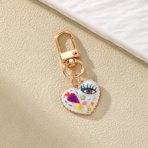 Colorful heart-shaped keychain with evil eye patterns on a ceramic tray backdrop