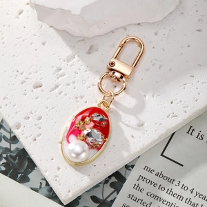 Macro detail of oval pendant keychain with red enamel, pearls, and crystals inlay