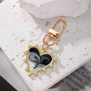 Detail of heart-shaped keychain with marble pattern and faux pearl edges on stone