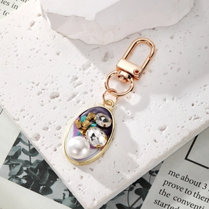 Vintage gold keychain with purple oval pendant featuring a large pearl and sparkling rhinestones