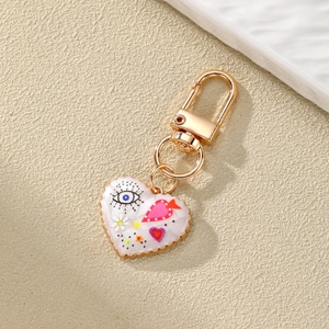 Detailed close-up of a pink heart keychain with evil eye patterns and golden metal clasp