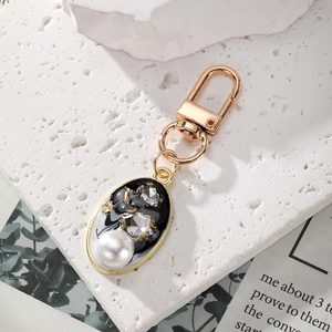 Detailed close-up of vintage oval keychain with pearls, crystals and black enamel finish