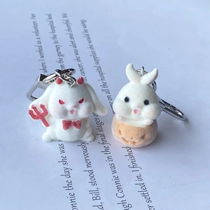 Detail view of cute flocked devil bunny and pumpkin rabbit keychain charms on a book