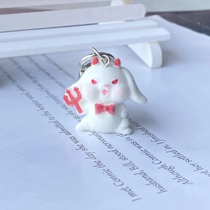 Close-up of white flocked rabbit demon keychain with red horns and trident detail