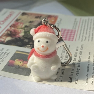 Detail of a white flocked snowman keychain with red hat and silver metal clasp