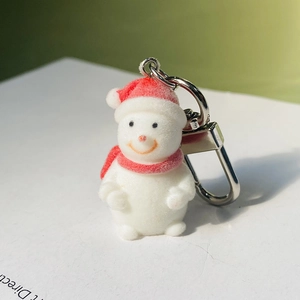 Cute flocked snowman keychain with red hat and scarf on a white card background