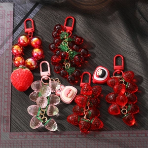Cute resin fruit keychains featuring translucent strawberry and cherry designs with charms