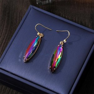 Élégantes boucles d'oreilles dorées avec cristaux colorés sur boîte à bijoux bleue