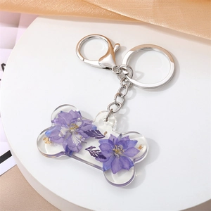 Détail d'un porte-clés en os de chien avec fleurs violettes et éléments en feuille d'or