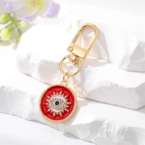 Détail d'un porte-clés bohème doré avec pendentif œil maléfique rouge et strass