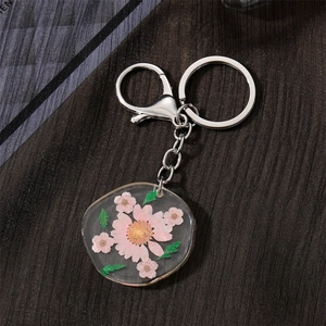 Detailed close-up of a handmade resin keychain featuring pink dried flowers and a silver clasp