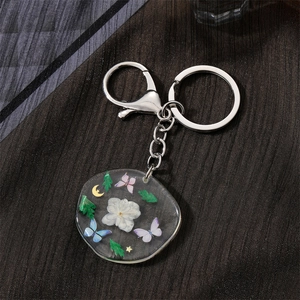 Irregular round resin keychain with dried flowers and butterfly charms in silver finish