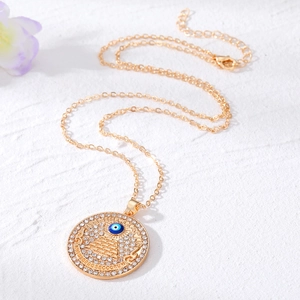 Golden Evil Eye pyramid coin necklace with white rhinestones on a textured background