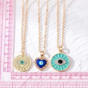 Evil Eye heart pendant necklaces with crystals and gold chains measured with a ruler