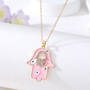 Detail of pink Hamsa Hand pendant with Evil Eye and rhinestones on a gold chain