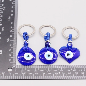 Macro view of blue glass Evil Eye charms in heart, drop, and round shapes with ruler