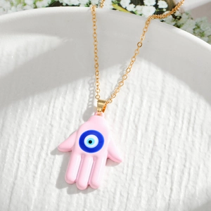 Detailed macro view of the pink Hamsa Hand pendant with Evil Eye on a golden chain