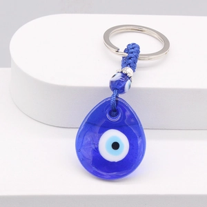 Macro shot of blue glass evil eye teardrop charm with metal ring and braided cord