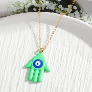 Detailed close-up of green Hamsa Hand pendant with Evil Eye on a decorative tray