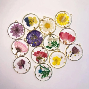 Flat lay of 12 resin floral pendants featuring real dried flowers and gold leaf accents
