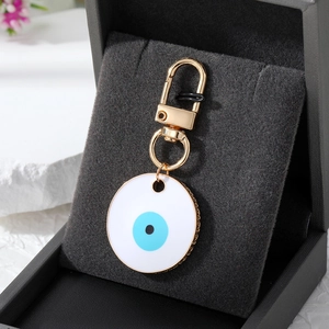 Golden Evil Eye keychain charm with white enamel and blue eye detail in a premium gift box