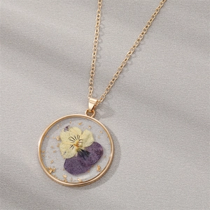 Detailed macro view of a gold round resin pendant with real dried flowers and gold flakes