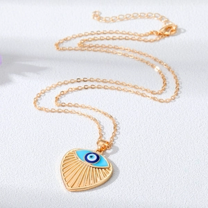 Collana a cuore dorata con pendente occhio blu malocchio su sfondo bianco pulito
