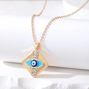 Gold evil eye diamond necklace with blue resin center on white stone pedestal