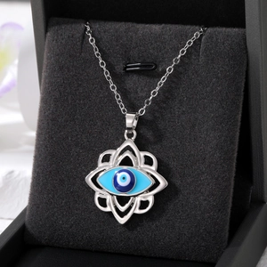 Close-up of silver evil eye necklace with hollow floral pattern in a velvet box