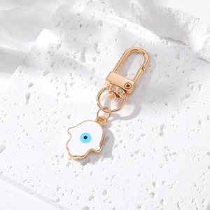 Golden Hamsa Hand keychain with blue Evil Eye charm on a textured stone surface