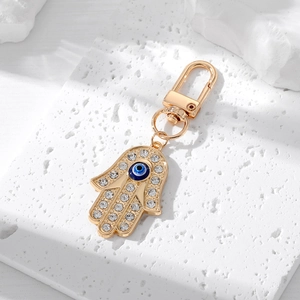 Hamsa Hand and Evil Eye keychain with crystals on a white stone background