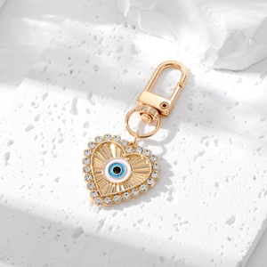 Detailed close-up of a golden heart evil eye keychain with rhinestones on a stone base