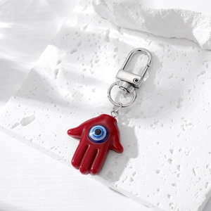 Détail macro du porte-clés main de Hamsa rouge avec pendentif œil bleu sur pierre