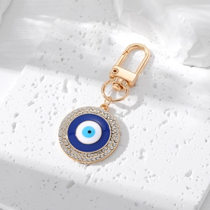 Detail of a golden Evil Eye keychain with blue enamel and sparkling white rhinestones
