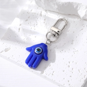 Porte-clés Main de Fatima bleu avec œil protecteur et fermoir argent sur pierre blanche