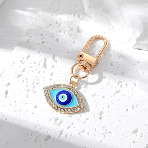 Close-up of a golden Evil Eye keychain with crystal rhinestones on a textured stone