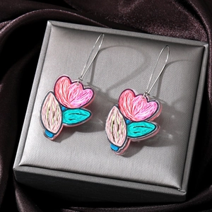 Macro detail of acrylic tulip flower drop earrings on a luxurious silk background