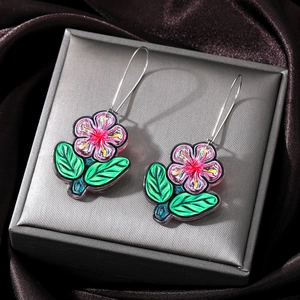 Detail of pink acrylic floral drop earrings with green leaves on metallic gift box