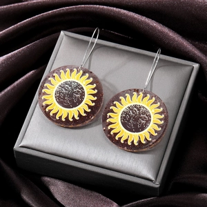 Cute acrylic sun face drop earrings with mystic yellow sunburst pattern on jewelry box