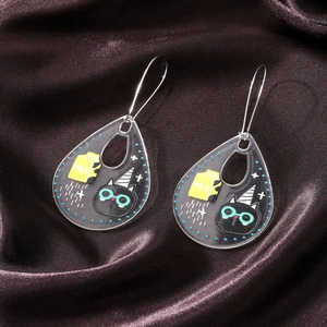 Detail of drop-shaped acrylic earrings with cute black cat and yellow milk box cartoon motifs