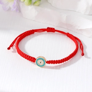 Adjustable red woven evil eye bracelet with a blue and gold sun-patterned pendant